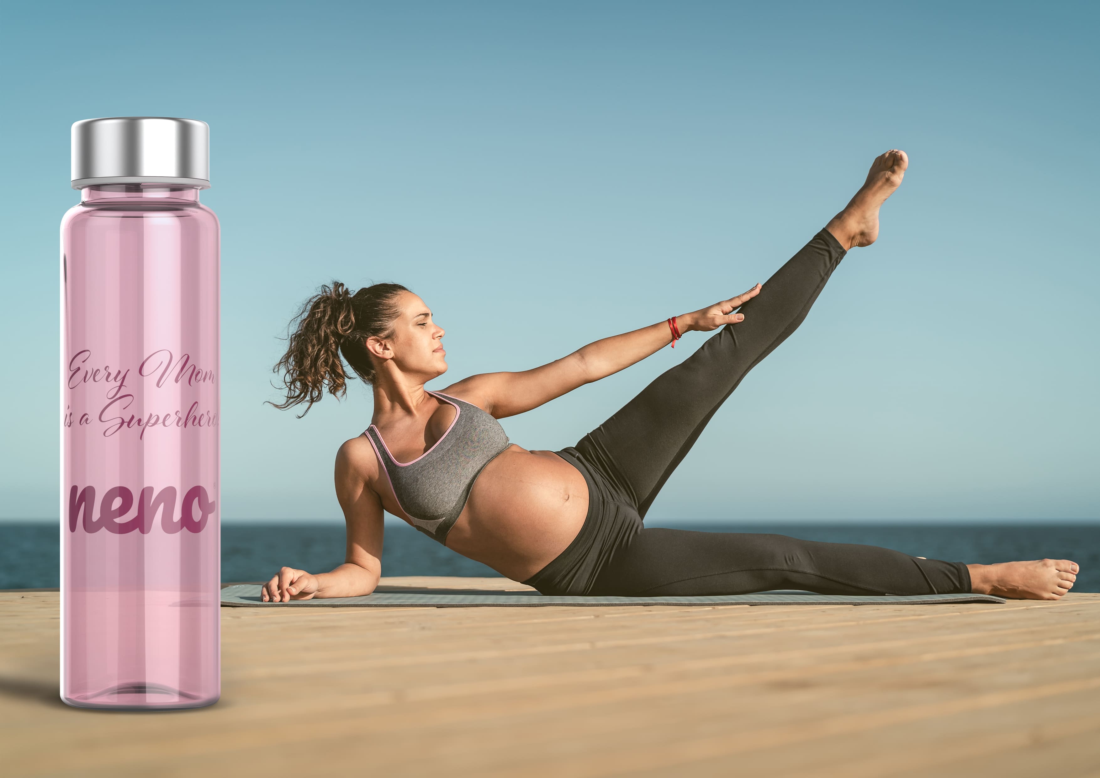 kobieta w ciąży cwiczy na plaży i obok bidon