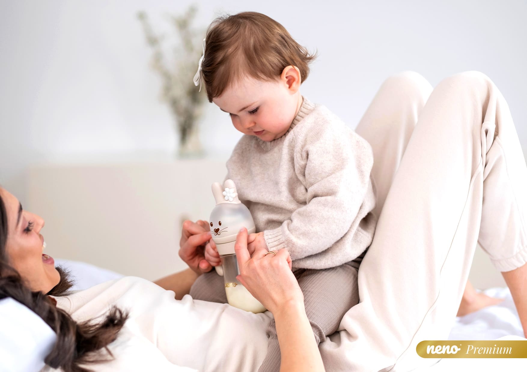 dziewczynka siedząca na brzuchu mamy i bawiąca sie Neno Mio