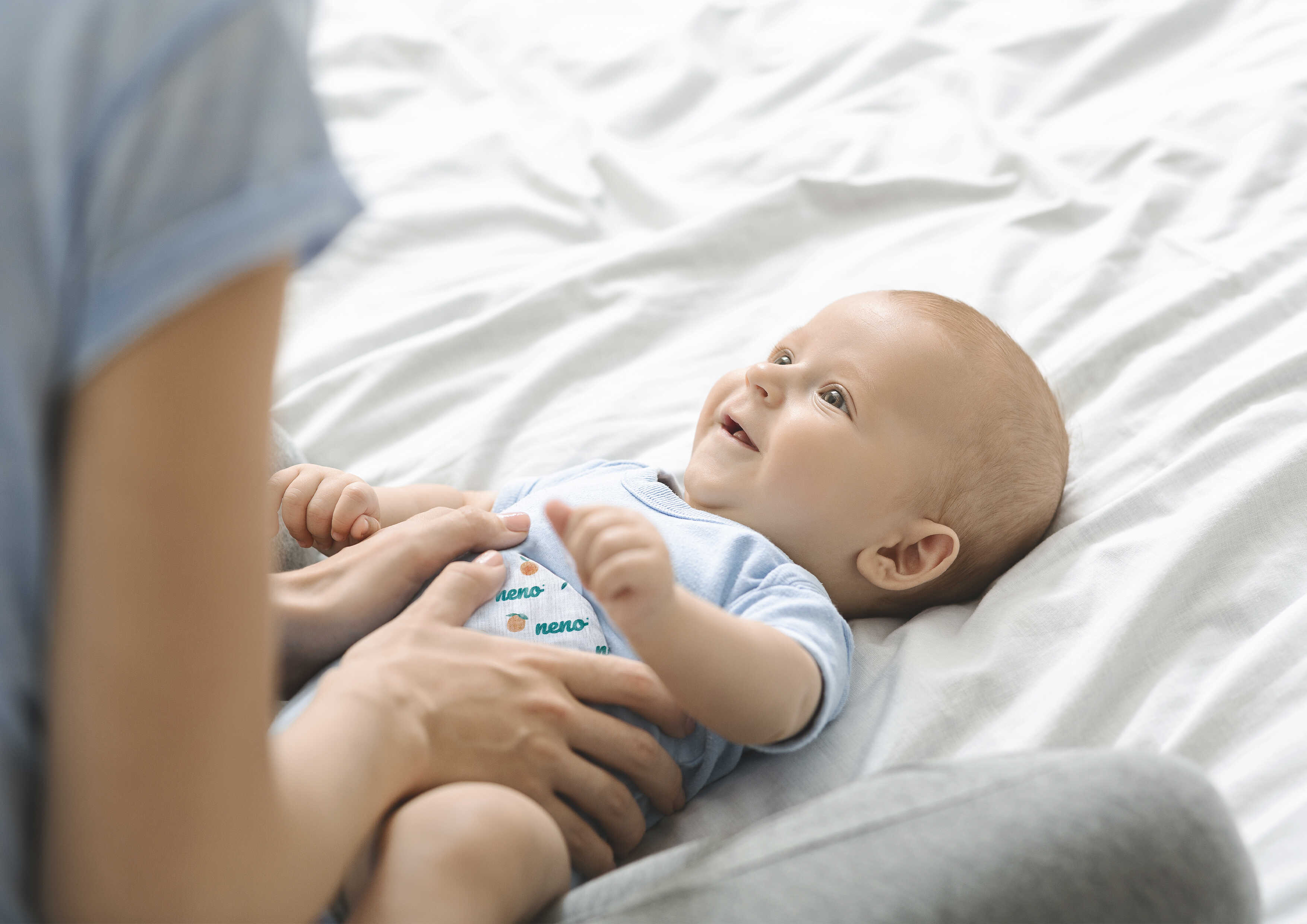 śmiejace się dziecko i mama przykładająca mu termofor do brzuszka