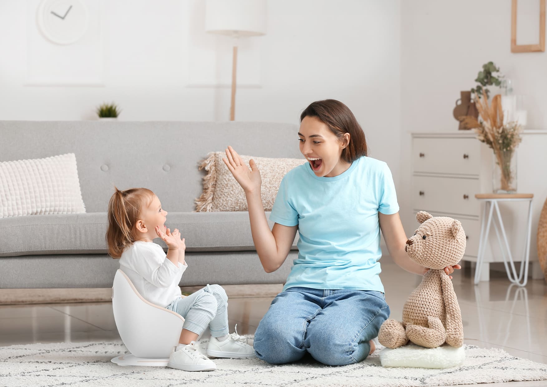 baby sitting on the potty and playing with mommy's teddy bear
